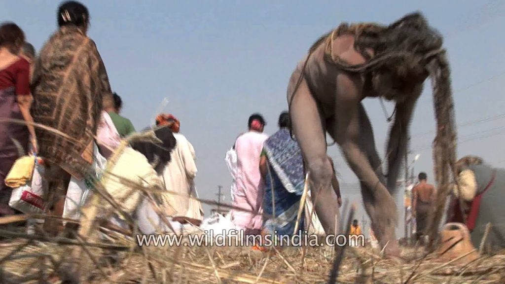 Western sadhus watch as Naga Sadhu applies human cremation ash on his body : Kumbh Mela, Allahabad