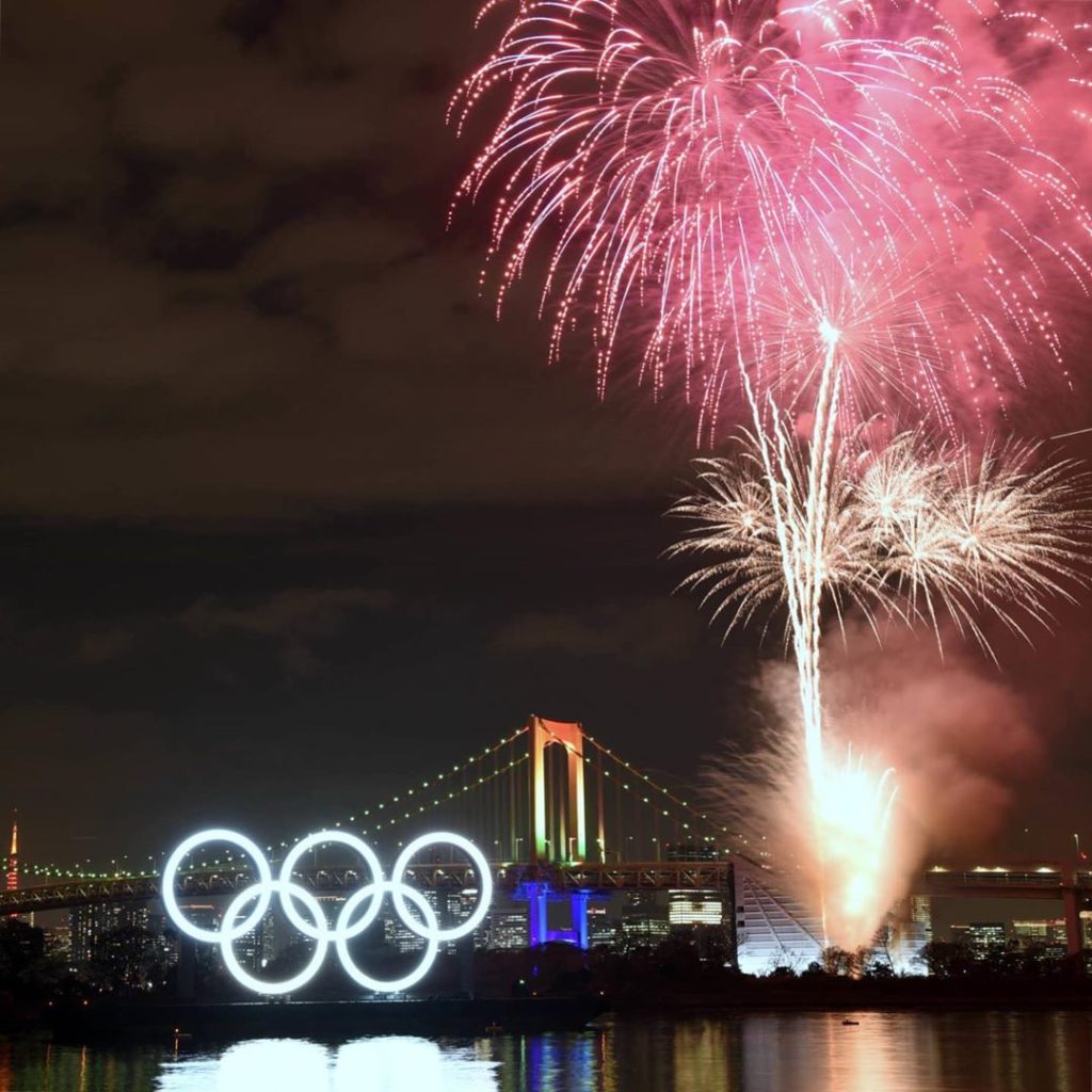 With the Olympic logo and Rainbow Bridge both lit up, fireworks explode over Tok...