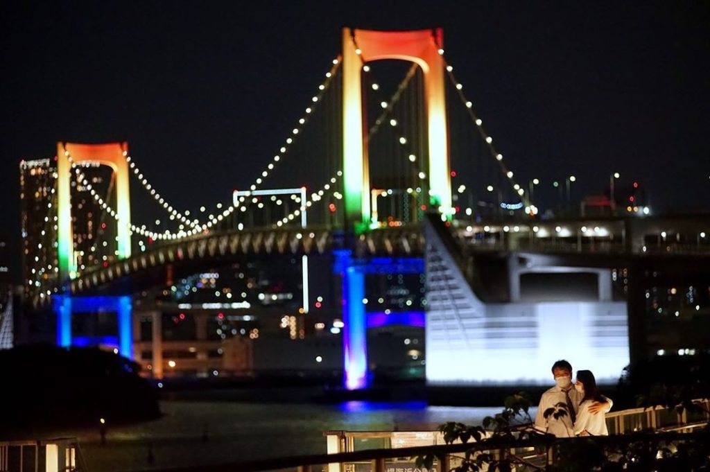 A couple embraces each other in Tokyo on Monday night with the Rainbow Bridge in...