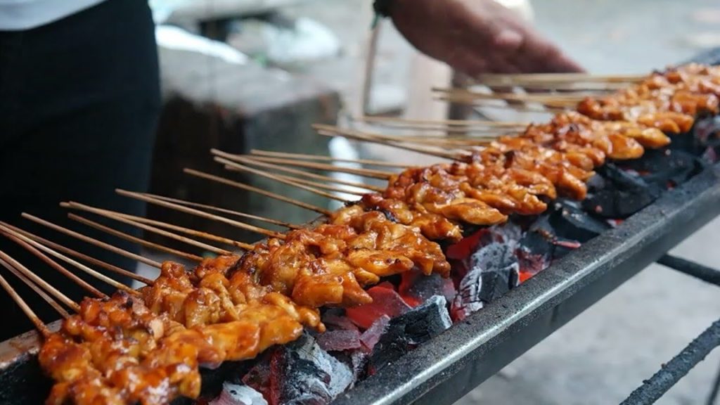 Indonesian street food - ( Sate Ayam ) Pieces of grilled chicken with thick peanut sauce