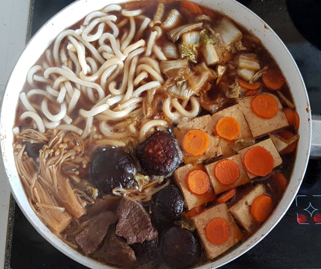 Homemade sukiyaki with beef, tofu, vegetables and udon