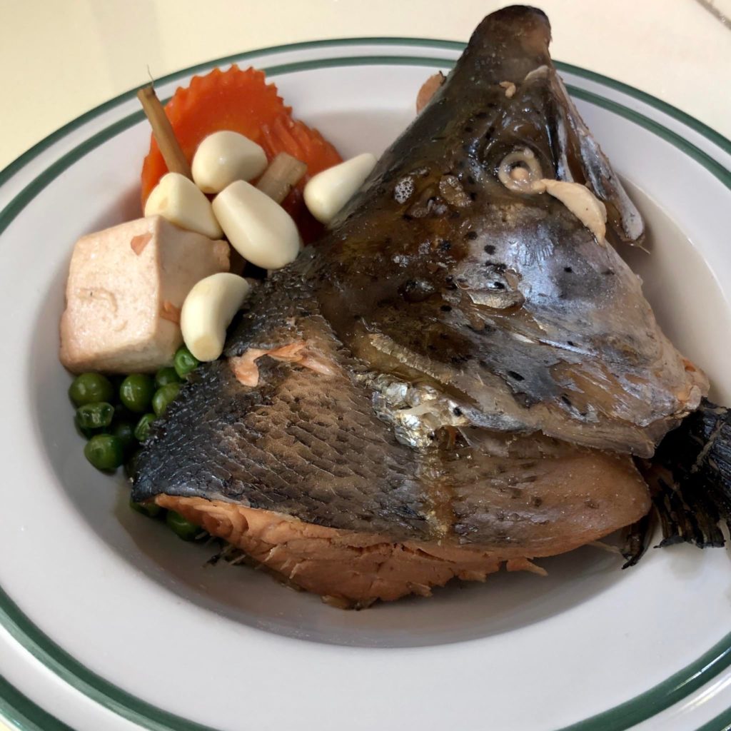Salmon Kabutoni (stewed salmon head) in a sweet soy sauce broth with super soft shiitake mushroom, tofu, carrots and peas.