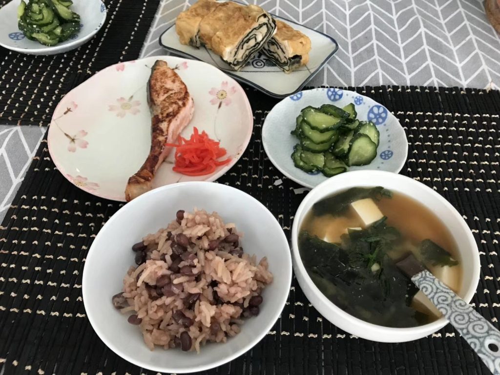 Japanese breakfast: azuki bean rice, grilled salmon, seaweed miso soup, shio koji pickled cucumber and nori sheet tamagoyaki.