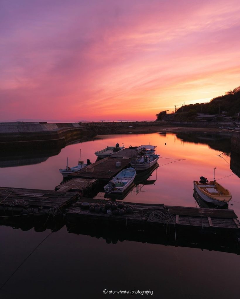 Enchanting reflections of a sky ablaze. The charming Ohama Fishing Port, tucked ...