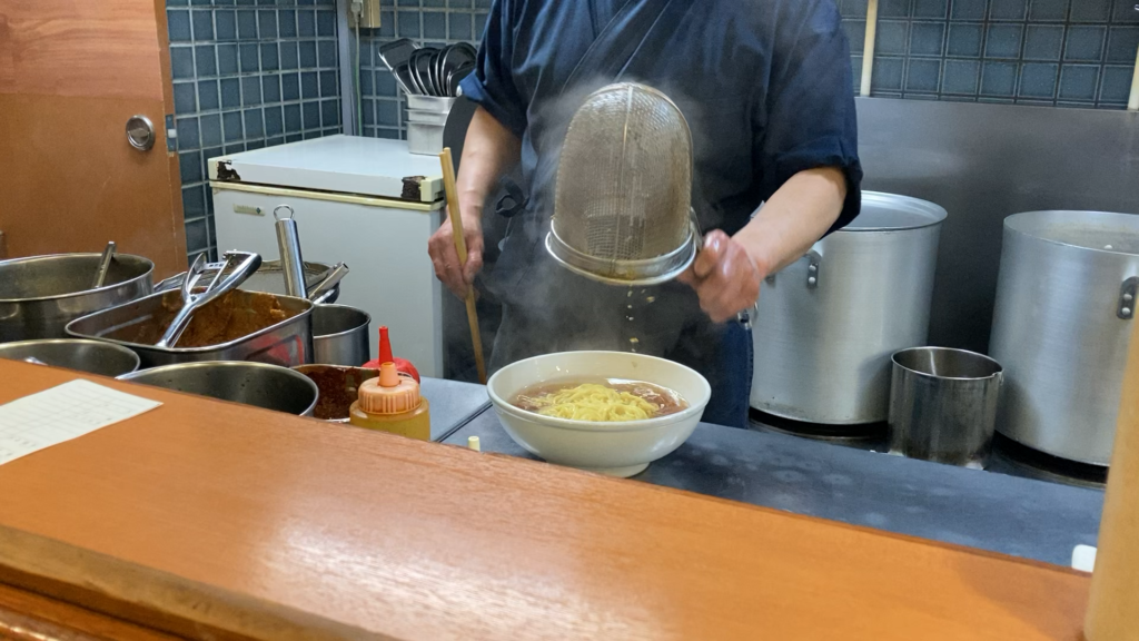 The final touches on a classic shoyu ramen bowl at 麺ロード in Tokyo