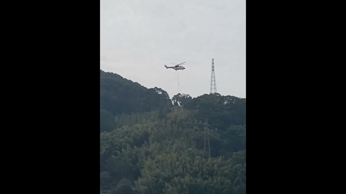 資材を運んで来たヘリが現場近くで徐々に降下する長崎彦山麓矢の平の送電鉄塔2塔目の建設工事
