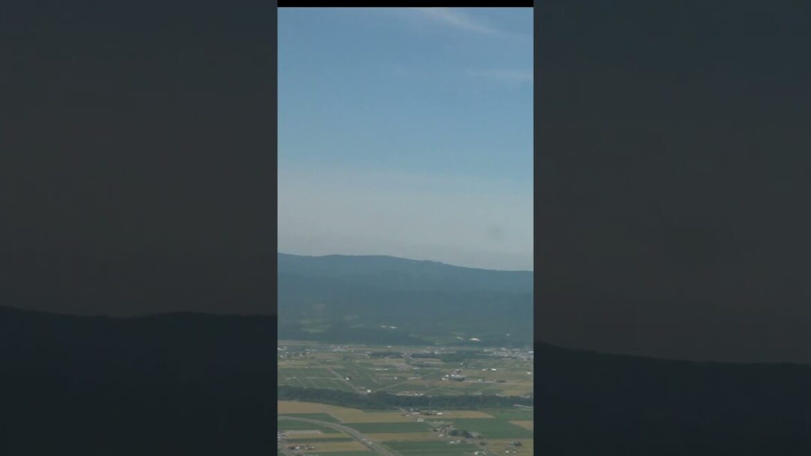 夏の北海道 旭川南部の農村地帯上空を低空で旋回していくAIRDO-B767機内窓からの景色