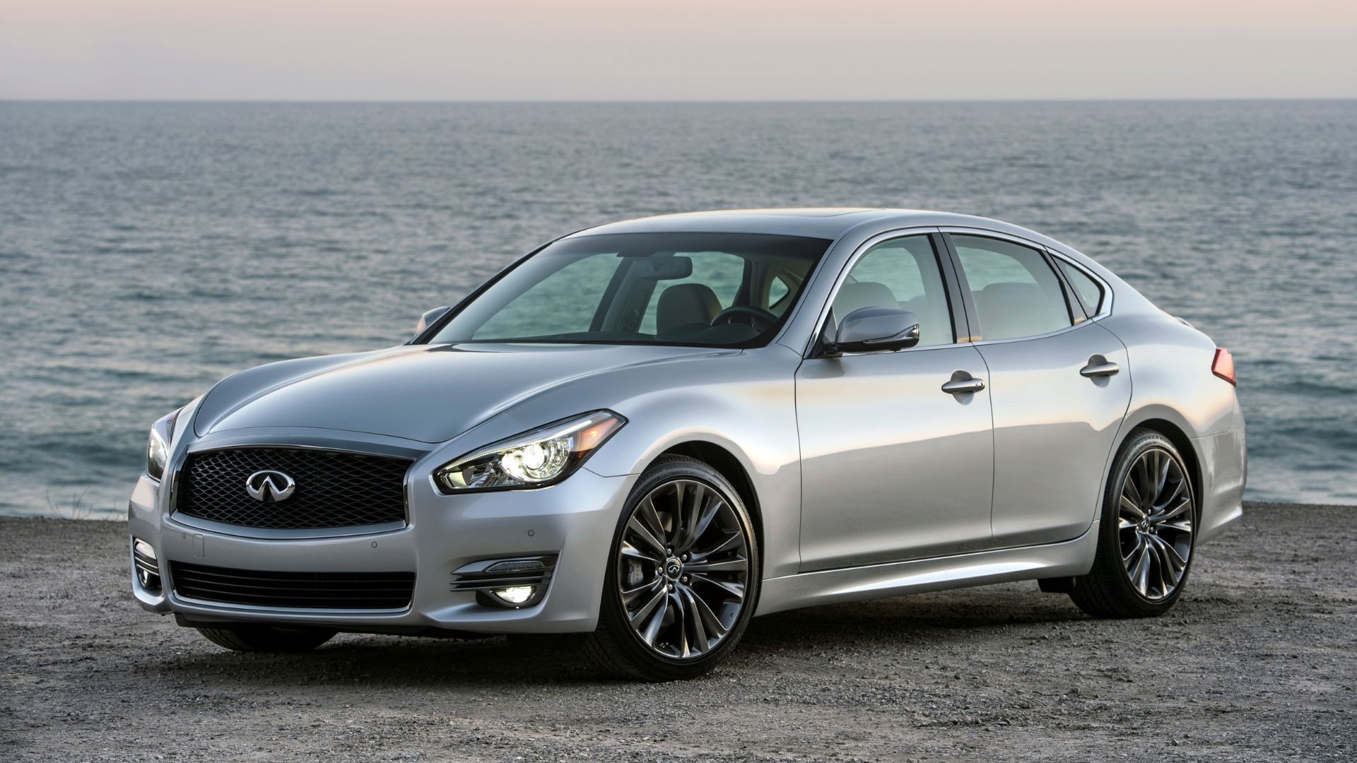 Front 3/4 view of a silver 2017 Infiniti Q70 parked on a beach.