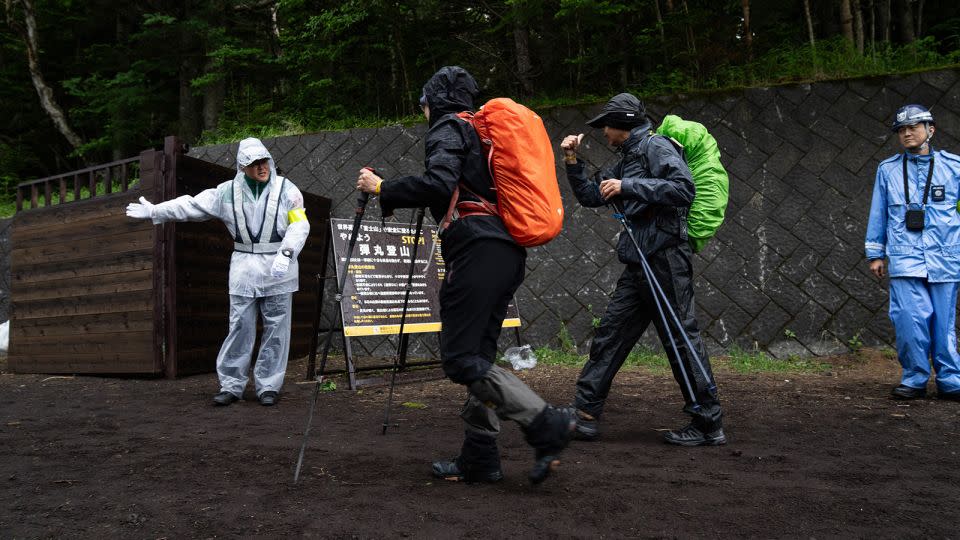 A staff member checks hikers for their wristbands, the proof of the hiking fee payment, at the Yoshida Trail of Mount Fuji. - Zhang Xiaoyu/Xinhua/Getty Images