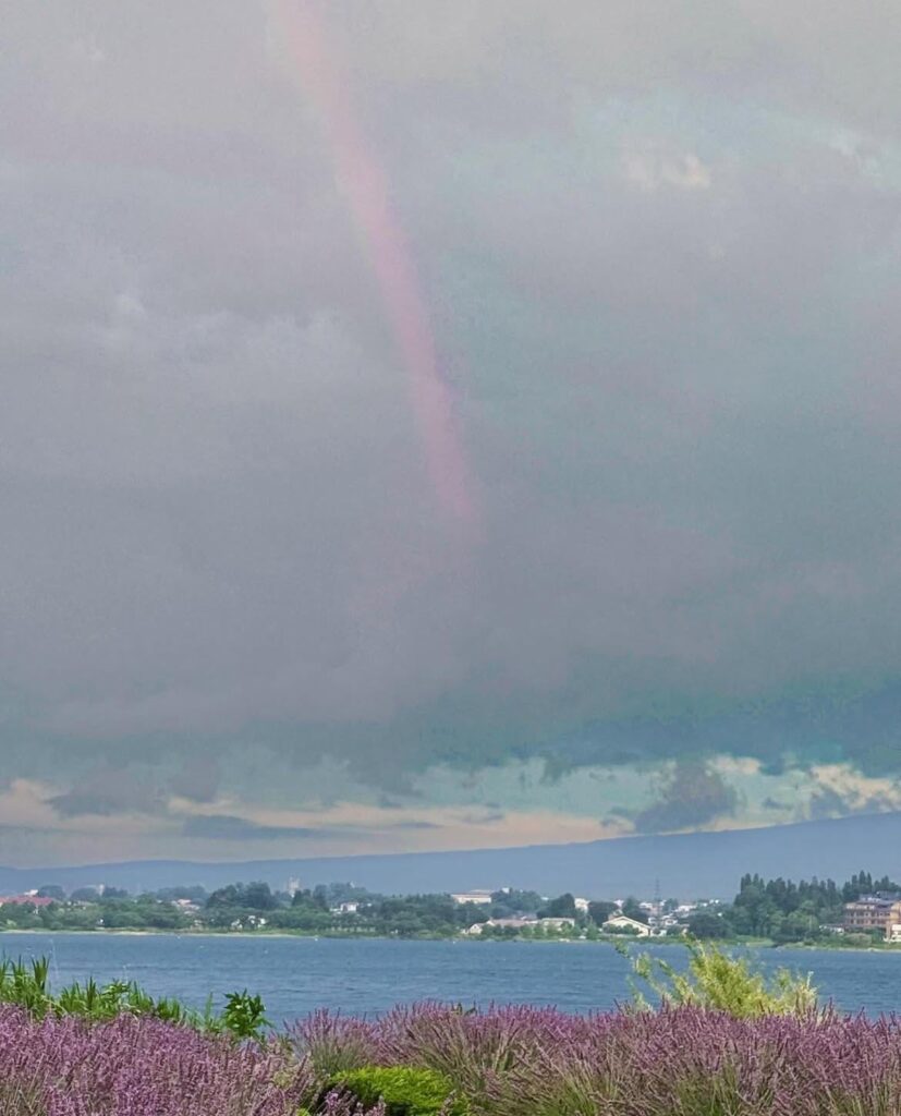 A rainbow at the base of Mount Fuji, hidden by clouds on a rainy day.