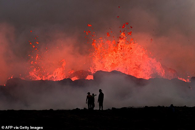 People watch flowing lava during an volcanic eruption near Litli Hrutur, south-west of Reykjavik in Iceland on July 10, 2023