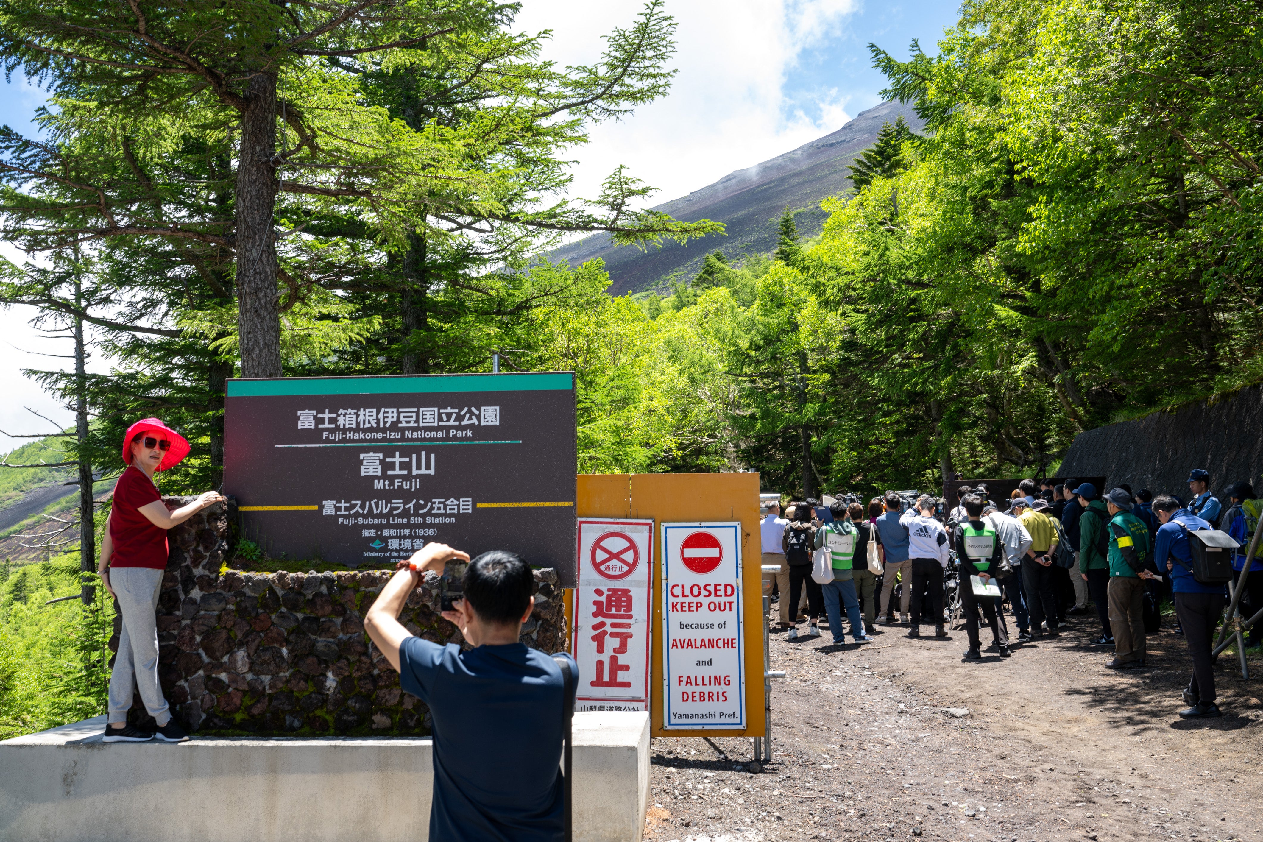 File. A tourist (L) poses in front of the gate of Fuji-Hakone-Izu national park near the Fuji Subaru Line 5th station, which leads to the popular Yoshida trail for hikers climbing Mount Fuji, at Narusawa, Yamanashi prefecture