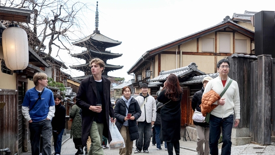 Tourists walk through the streets by Yasaka Pagoda (behind) during a visit to the city of Kyoto. (Photo by PAUL MILLER / AFP)
