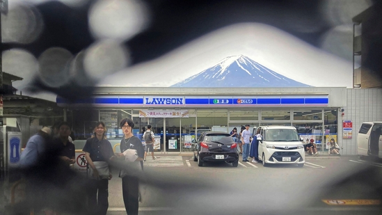 Mt. Fuji is seen through a hole on a black screen installed across from a convenience store in Fujikawaguchiko town, Yamanashi prefecture, central Japan. The town that erected the huge black screen last week in an attempt to stop tourists from snapping photos of Mount Fuji and overcrowding the area has discovered holes in the screen and is working to repair them, officials said Tuesday. (Photo by Kyodo News via AP)