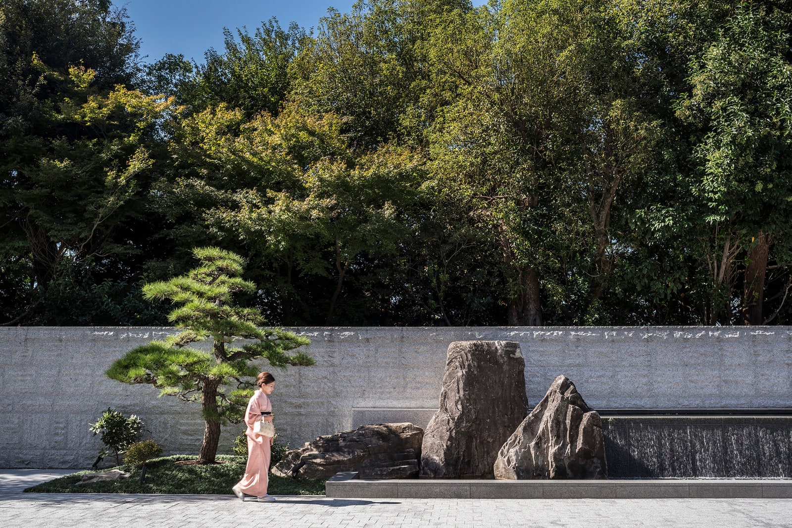 Image may contain Plant Tree Clothing Dress Formal Wear Fashion Gown Person Potted Plant Walking and Tree Trunk