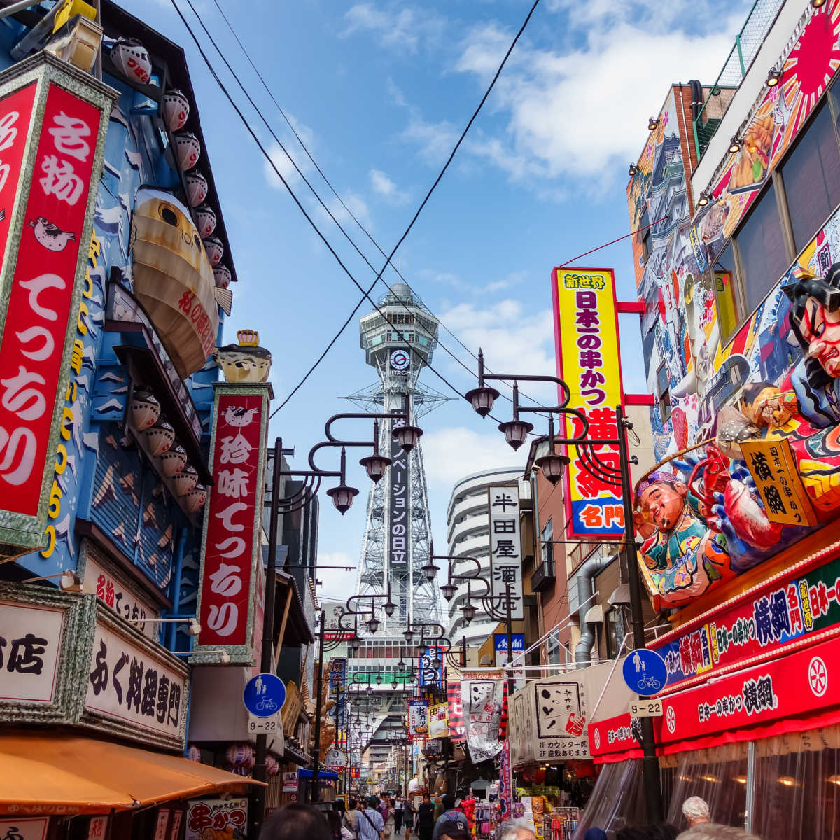 Vibrant street in Osaka with Tsutenkaku tower  in background