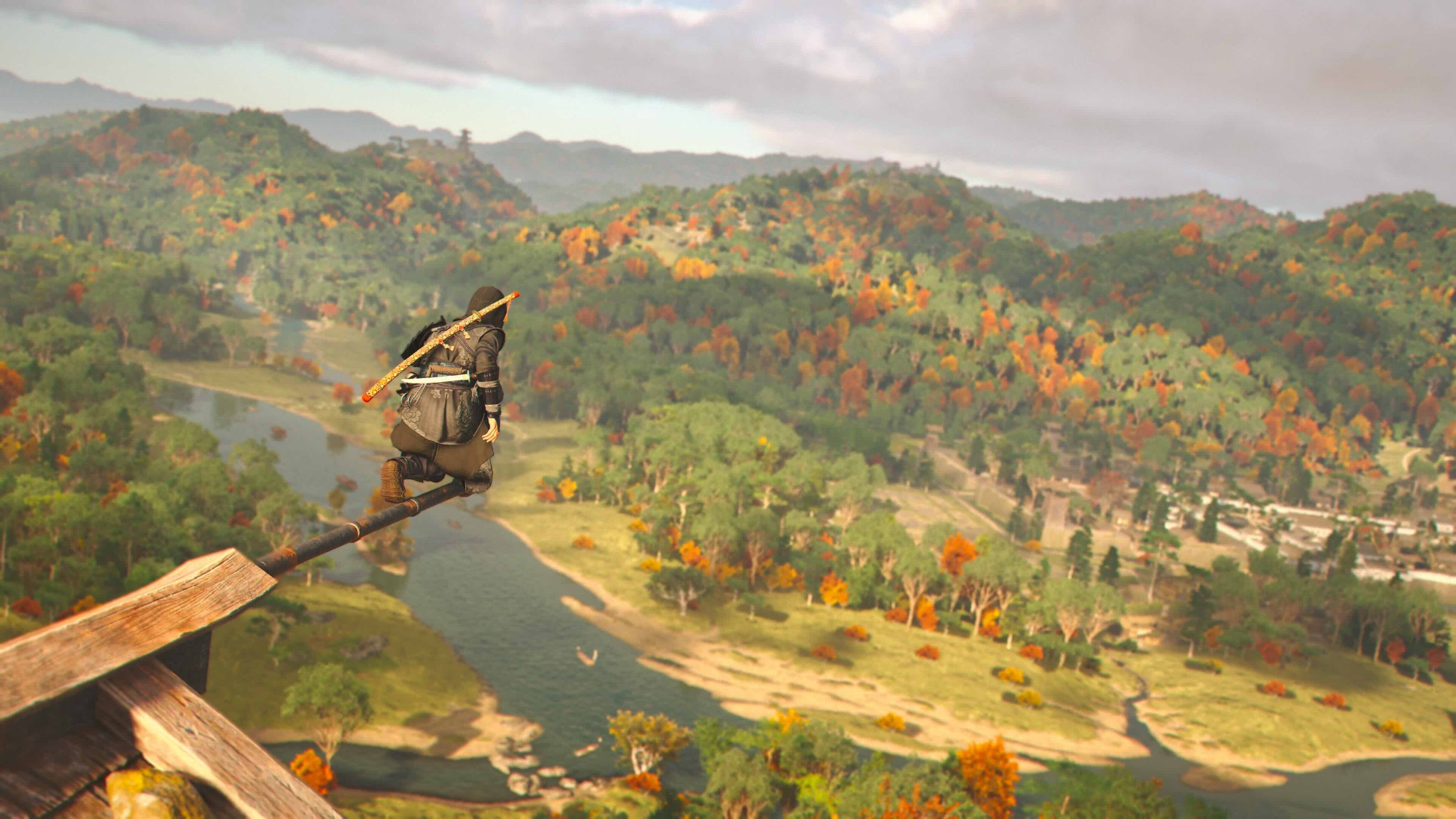 Naoe stands on a ledge over autumnal hills in Assassin’s Creed Shadows