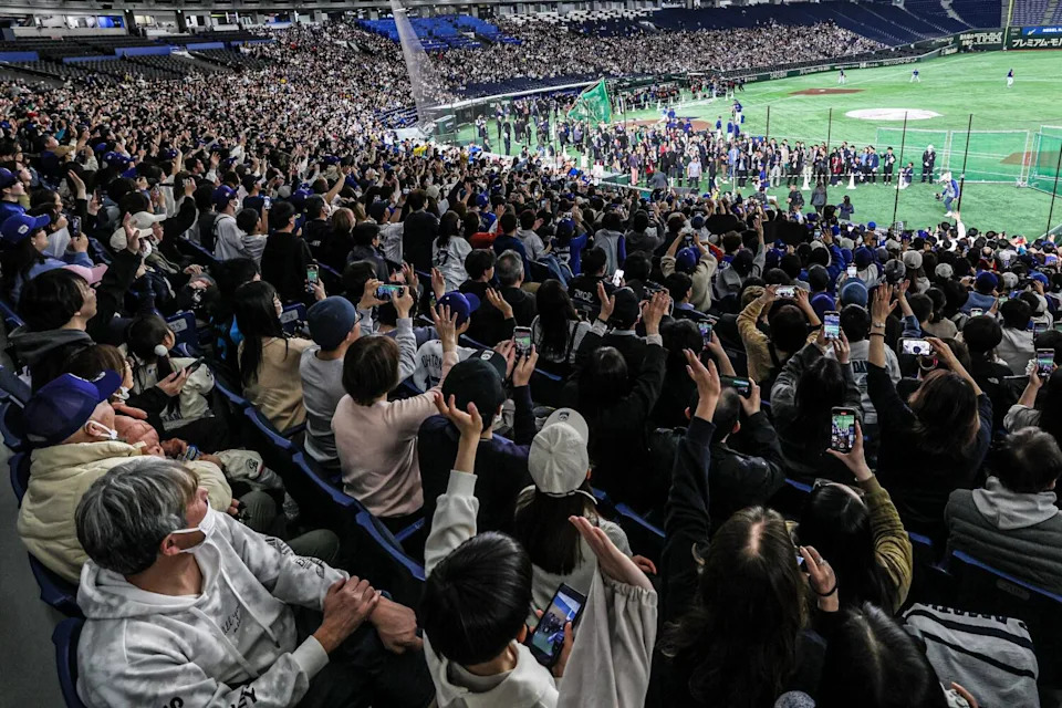 Fans waving at Shohei Ohtani as he leaves the field following a workout with the Dodgers in Tokyo
