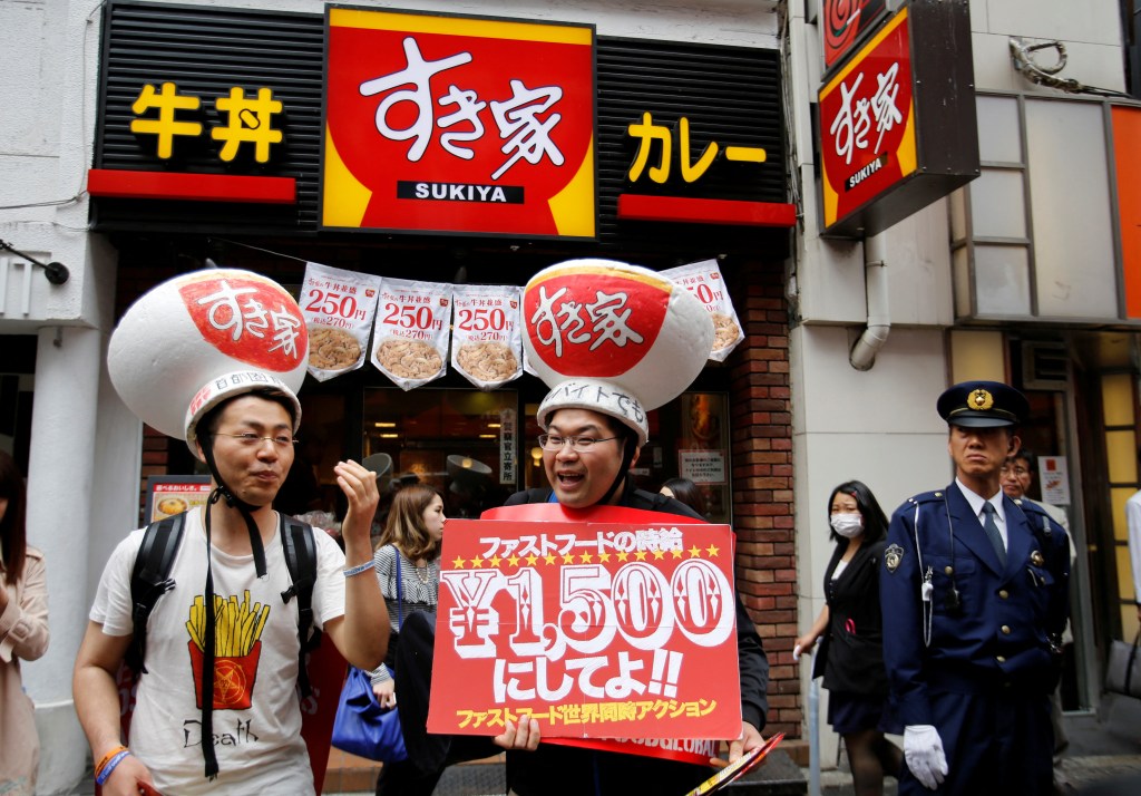 Demonstrators wearing hats featuring beef bowls from Sukiya fast-food restaurant, take part in a protest to demand higher wages for fast-food workers in front of a Sukiya restaurant in Tokyo's Shibuya shopping and amusement district May 15, 2014