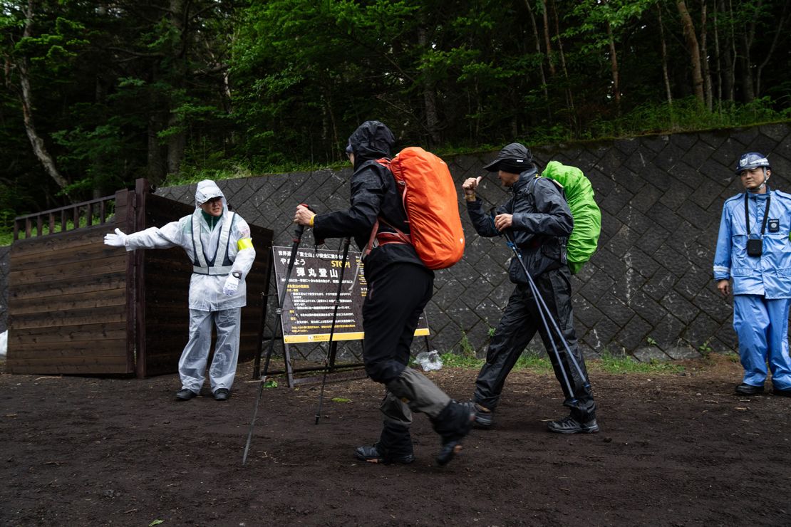 A staff member checks hikers for their wristbands, the proof of the hiking fee payment, at the Yoshida Trail of Mount Fuji.