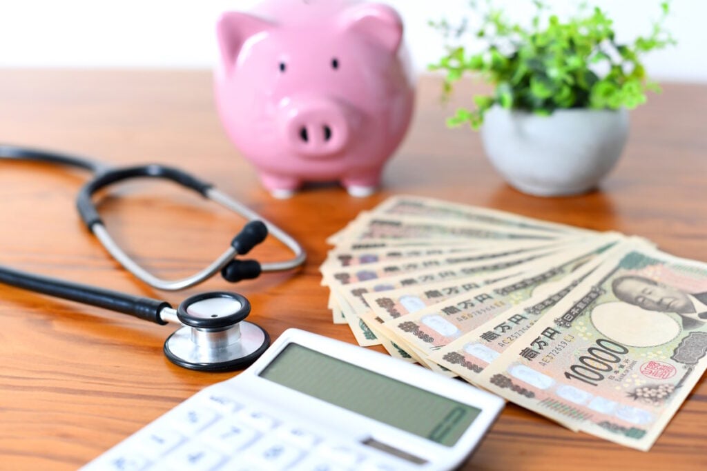 Picture of a piggy bank, yen bills, a calculator, and a stethoscope