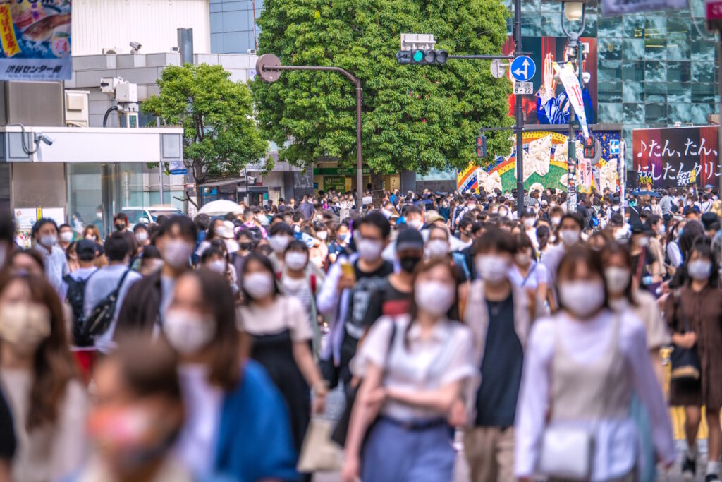 Young people walking in a crowd on the sidewalk towards the camera