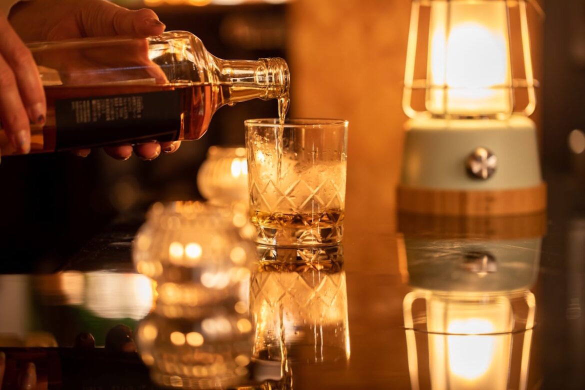 Woman pouring a drink at a snack bar from a bottle of whisky
