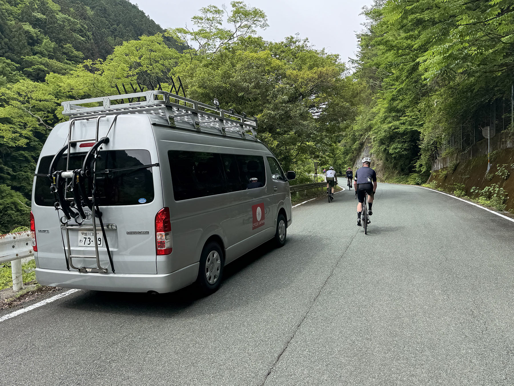 ride and seek support van driving next to cyclists in japan.