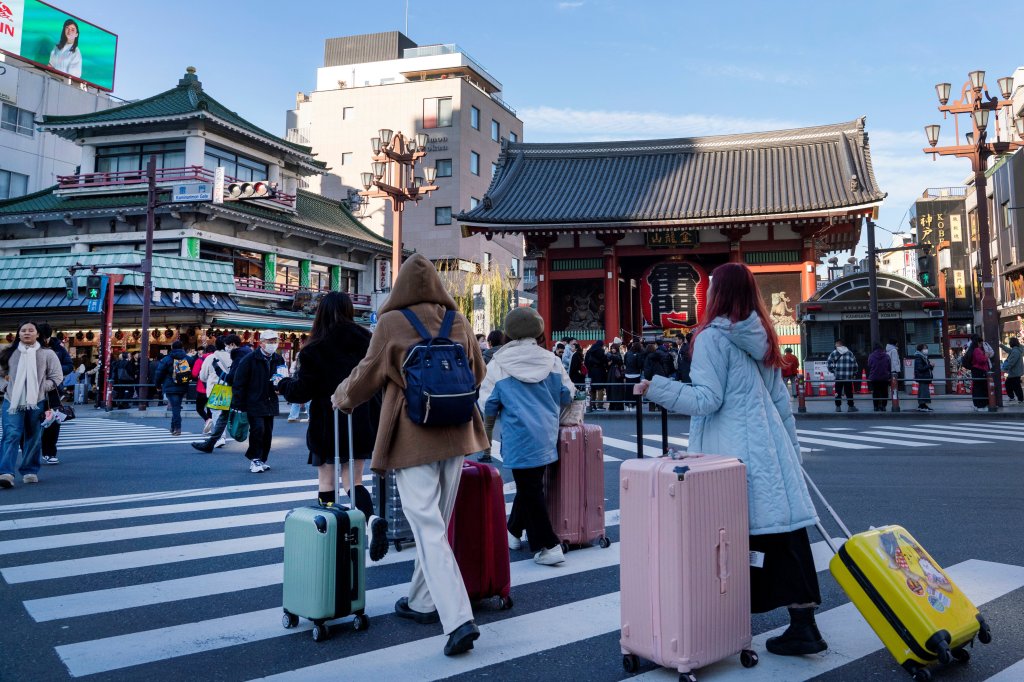 Tourists cross a street in front of Sensoji Temple in Asakusa, Tokyo on January 14, 2025.