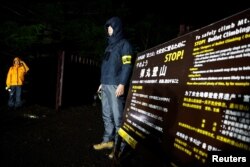 Yamanashi prefectural government office staff members stand guard next to a newly-built trail gate for admission on the fifth stage of the slopes of Mount Fuji, in Fujiyoshida, Yamanashi Prefecture, Japan, July 1, 2024.