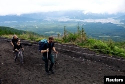 Climbers walk on Fuji Yoshidaguchi Trail (Yoshida Route) on the first day of the climbing season on the slopes of Mount Fuji, in Fujiyoshida, Yamanashi Prefecture, Japan, July 1, 2024.