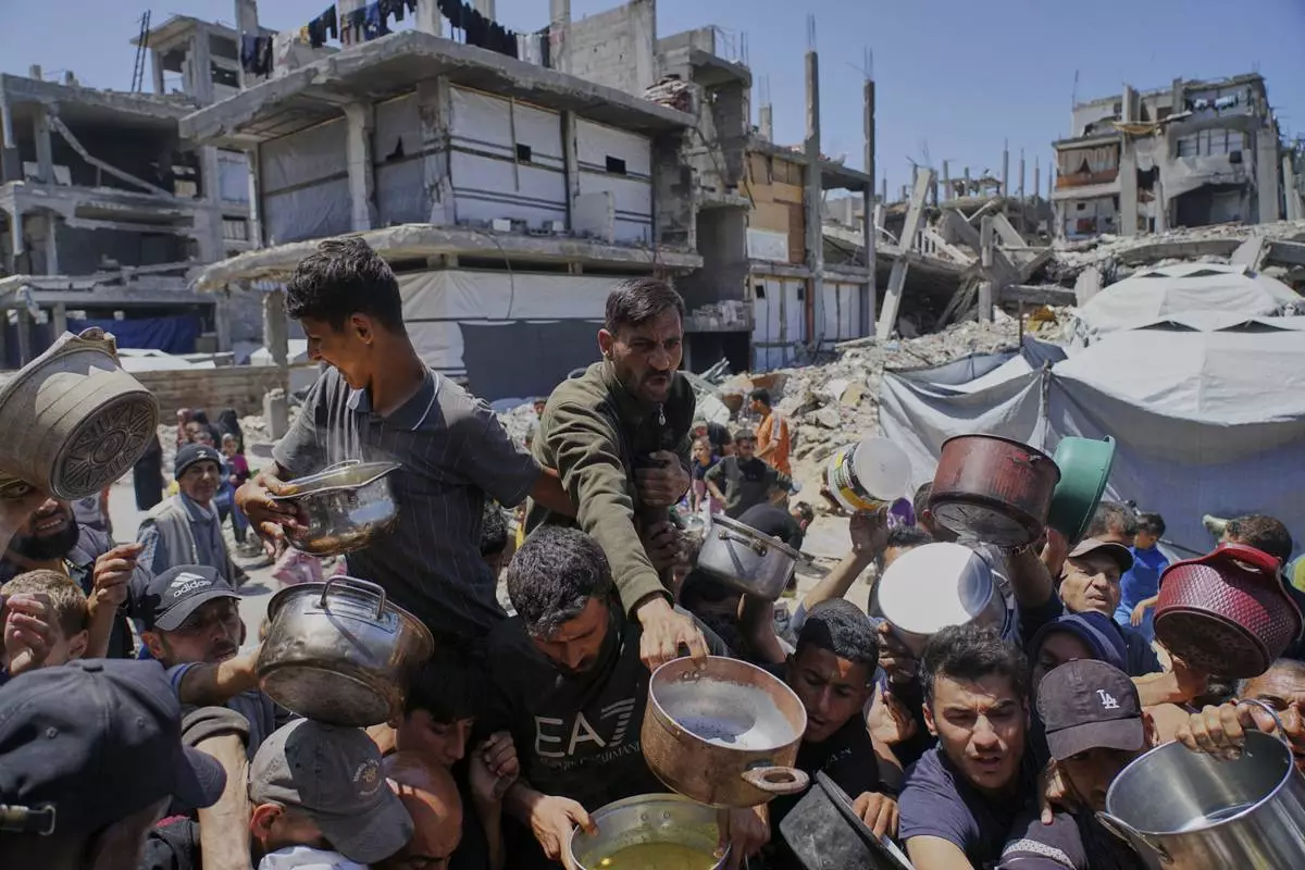 Palestinians receive donated food at a distribution center in Beit Lahia, northern Gaza Strip, Tuesday, April 29, 2025. (AP Photo/Jehad Alshrafi)