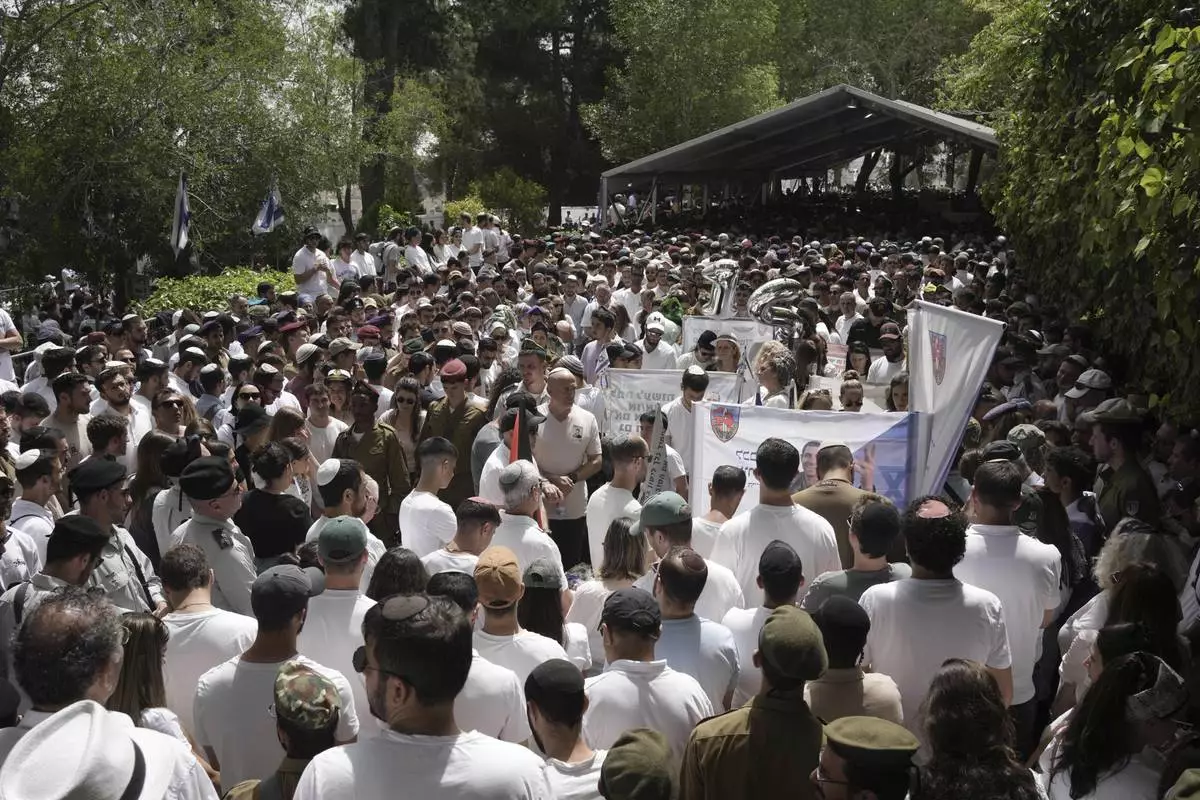 People and Israeli soldiers stand during two minutes of silence as air raid sirens sound marking the Israel's annual Memorial Day for the fallen soldiers and victims of nationalistic attacks at Mount Herzl military cemetery in Jerusalem, Wednesday, April 30, 2025. (AP Photo/Maya Alleruzzo)