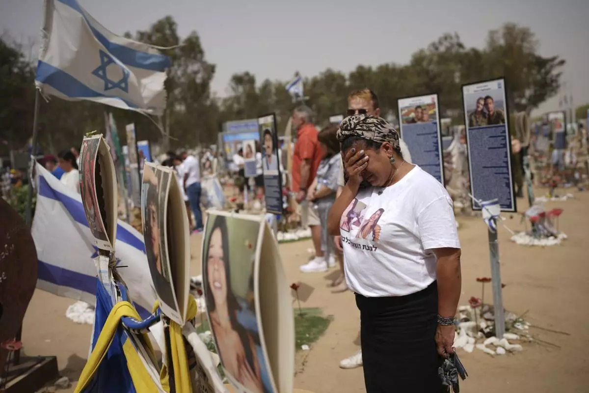 People stand still to observe two minutes of silence as air raid sirens sound marking the Israel's annual Memorial Day at the site of Oct. 7, 2023 attack by Hamas militants at the Nova music festival near Kibbutz Reim, southern Israel, Wednesday, April 30, 2025. (AP Photo/Ohad Zwigenberg)