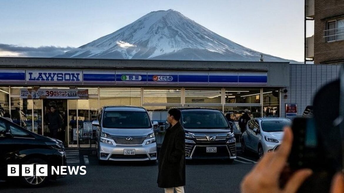 An image showing a photo being taken of a person standing in front of a Lawson shop, with Mount Fuji in the background