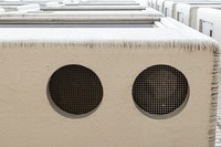 Vents for an air-conditioning compressor unit are seen on the bottom of a bay window at the 