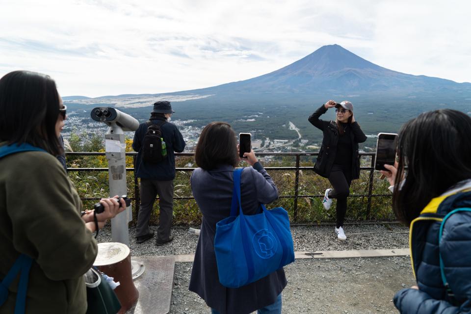 Tourist posing with Mount Fuji in distance.