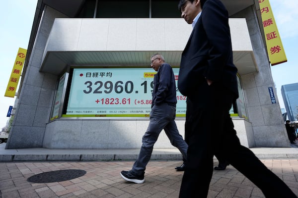 Men walk past monitors showing Japan's Nikkei 225 index at a securities firm in Tokyo, Tuesday, April 8, 2025. (AP Photo/Hiro Komae)