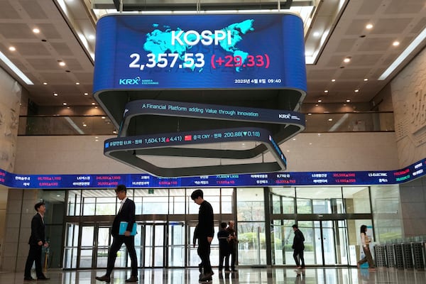 People pass by a screen showing the Korea Composite Stock Price Index (KOSPI) at the Korea Exchange in Seoul, South Korea, Tuesday, April 8, 2025. (AP Photo/Ahn Young-joon)