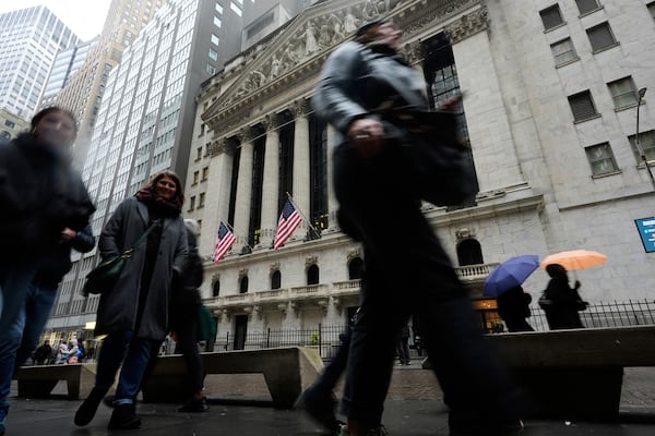 People walk past the New York Stock Exchange in New York, Monday, April 7, 2025. (AP Photo/Seth Wenig)