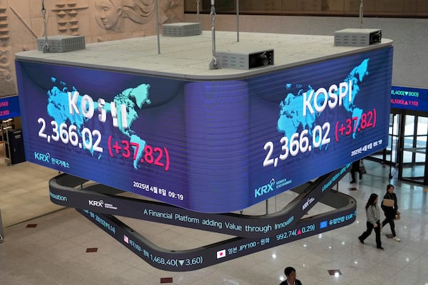 People pass by a screen showing the Korea Composite Stock Price Index (KOSPI) at the Korea Exchange in Seoul, South Korea, Tuesday, April 8, 2025. (AP Photo/Ahn Young-joon)
