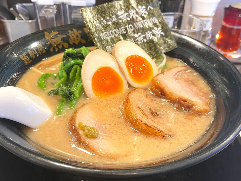 A bowl of Ramen with an egg, pork, and greens.