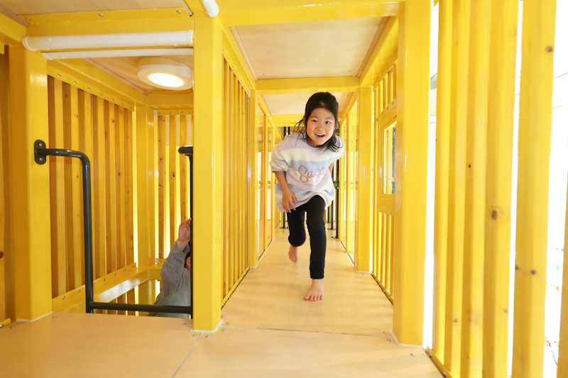 ANO NE Playspace - yellow metal girders forming a running corrider