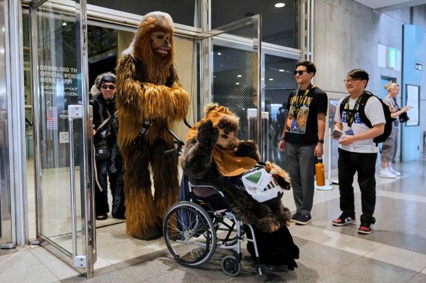 Star Wars fans wearing costumes of Chewbacca, left, and Widdle...