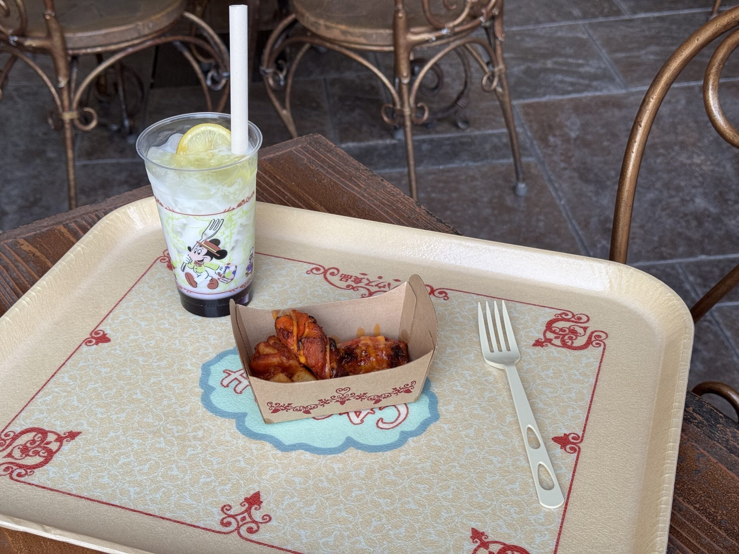 A tray with a cold drink, spicy chicken wings, and lemon at the 2025 Food and Wine Festival, Tokyo DisneySea.