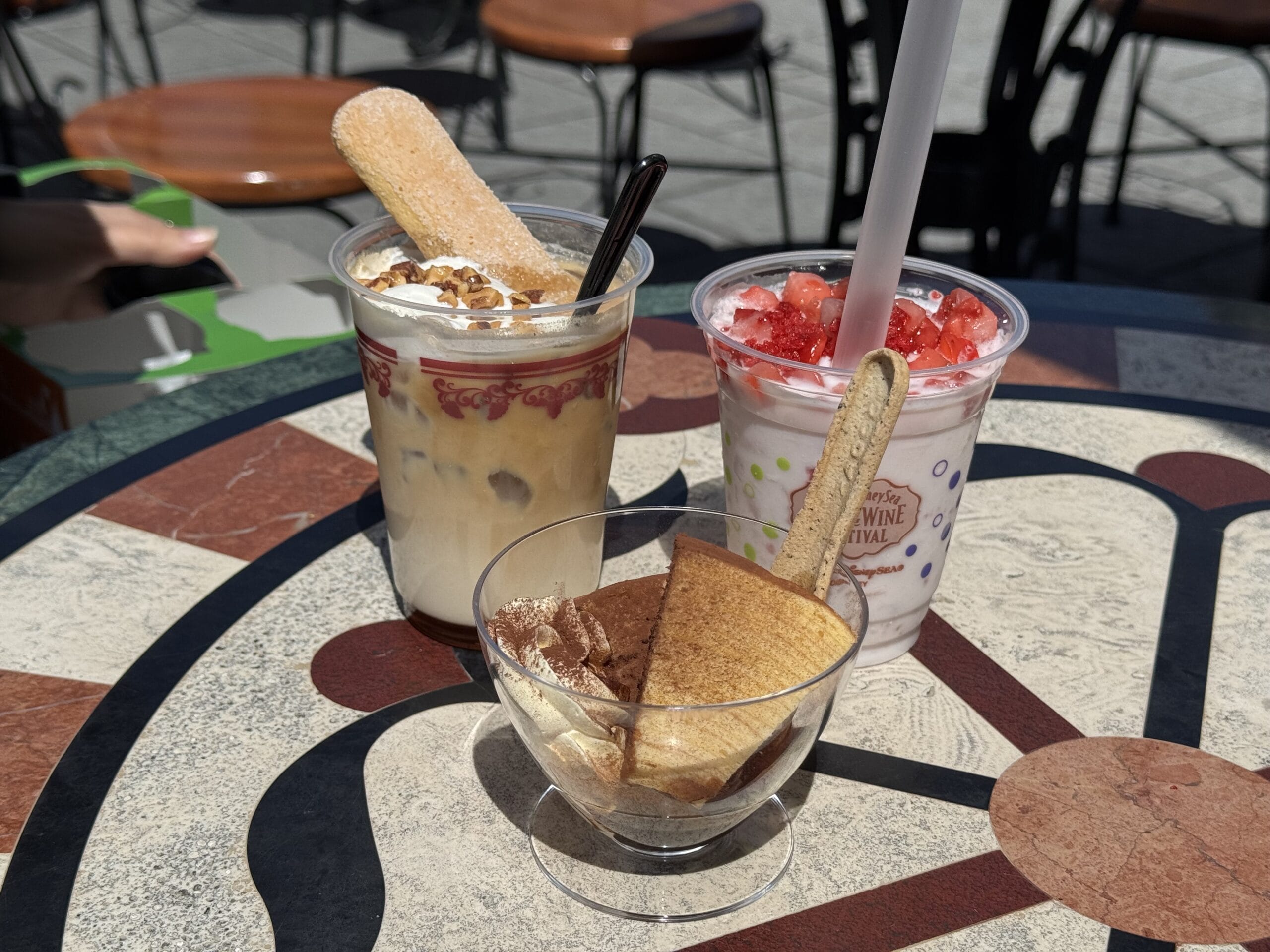 Three dessert drinks and tiramisu on a colorful table at Tokyo DisneySea’s 2025 Food and Wine Festival.