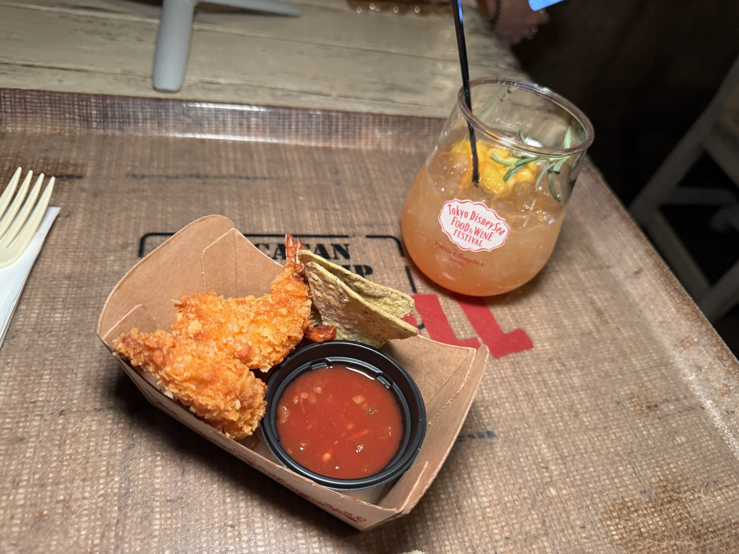 A tray with fried shrimp, chips, salsa, and an orange drink served at the 2025 Food and Wine Festival.