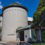 A cylindrical shaped tower with an entrance jutting out.