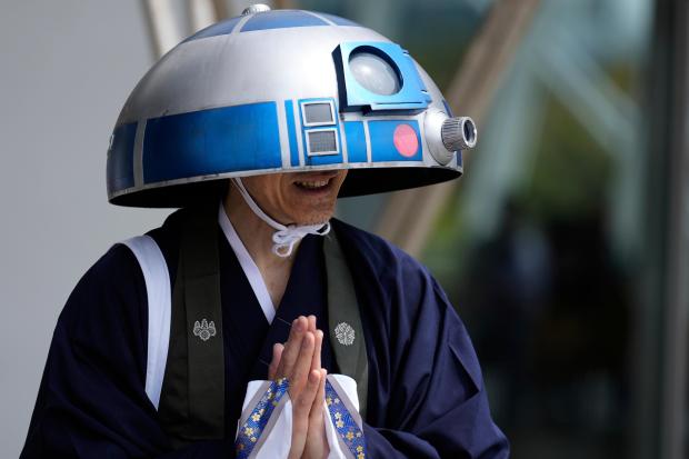 A Star Wars fan in an R2-D2 costume poses for...