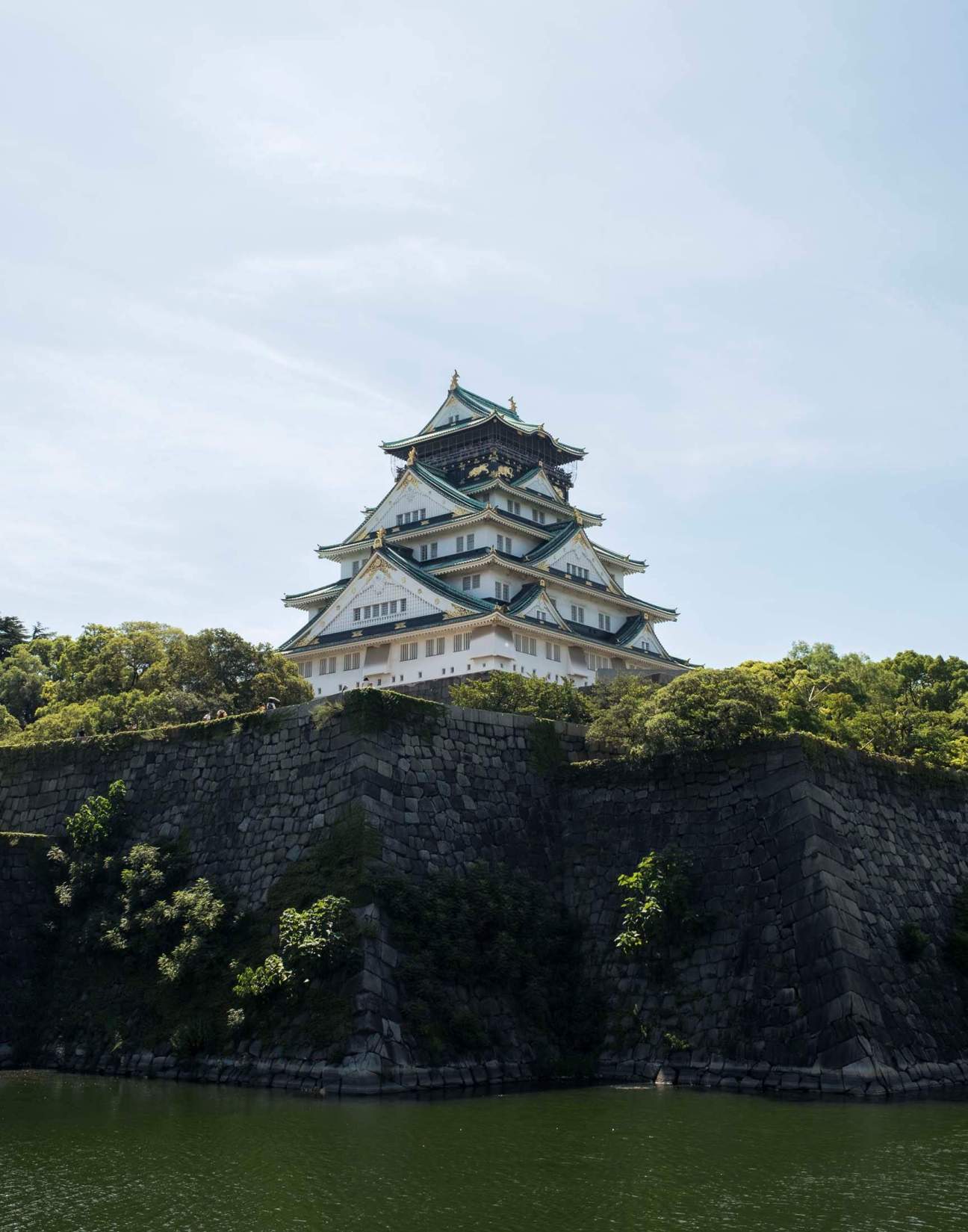 A photo of the Osaka castle with the castle wall and moat in the foreground.